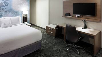 Hotelkamer met een groot bed, bureau met stoel, flatscreen televisie en spiegel.