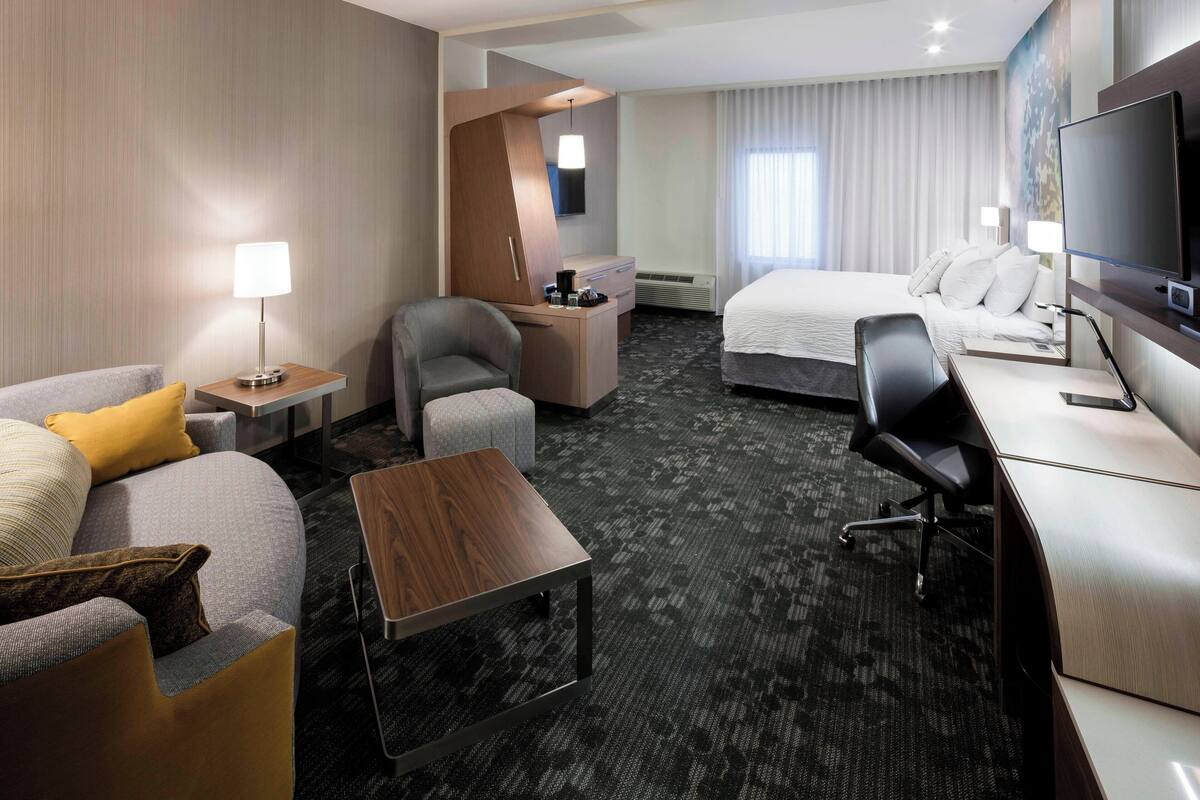 A hotel room with a sofa, armchair, desk, and a bed.