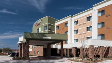 Hotel con patio, entrada cubierta, varios pisos y cielo despejado.