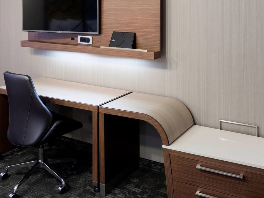 A modern office desk with a chair, a small shelf above the desk, and a drawer unit to the right.