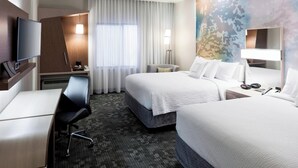 A hotel room with two beds, a desk, a chair, a TV, and a large window with curtains. - Courtyard by Marriott Houston North/Shenandoah (Shenandoah)