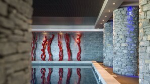 Een modern interieur met stenen zuilen, een glazen balustrade en abstracte rode muurkunst.
