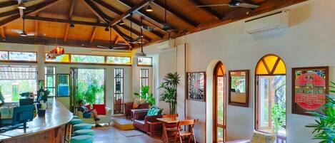 A spacious lobby with a wooden ceiling, a bar area, seating arrangements, and large windows allowing natural light.