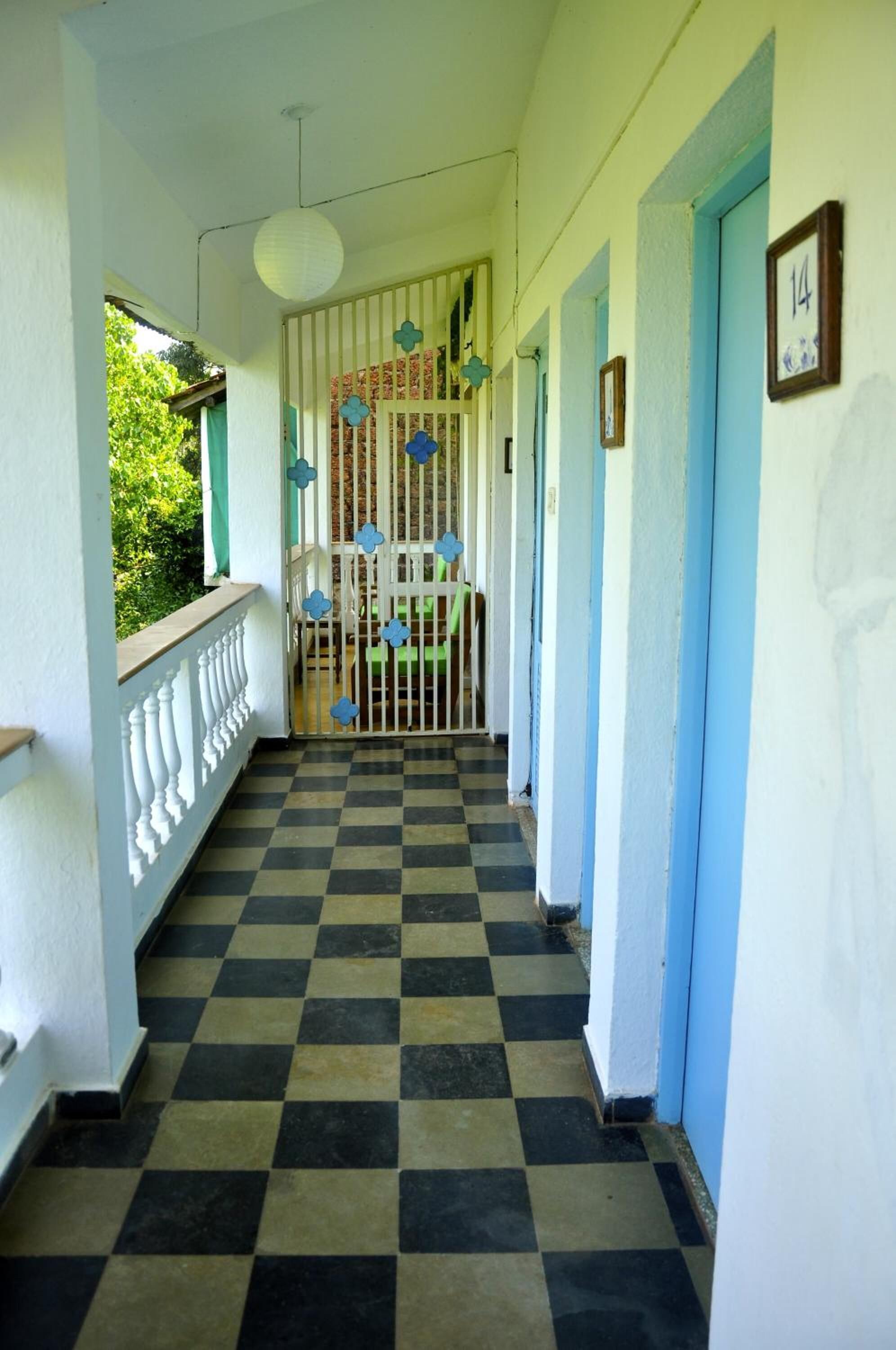 Un pasillo con piso a cuadros, barandal blanco y puertas azules.