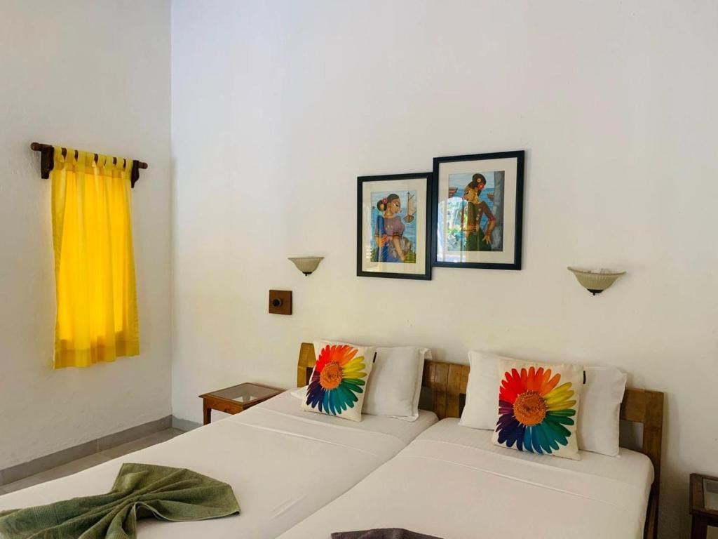 Habitación de hotel con dos camas, una cortina amarilla y dos lámparas fijadas a la pared.