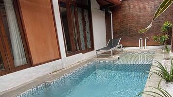 A swimming pool with a geometric tile pattern, surrounded by a brick wall and a wooden deck.