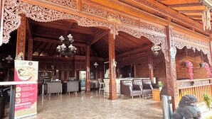 Un vestíbulo de hotel con arquitectura de madera ornamentada, una recepción y zonas de estar.