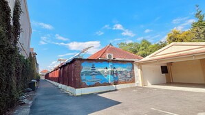 A street view with a building featuring a mural, a parking lot, and a clear blue sky. - Chrome Hotel & Resort Solo (Colomadu)