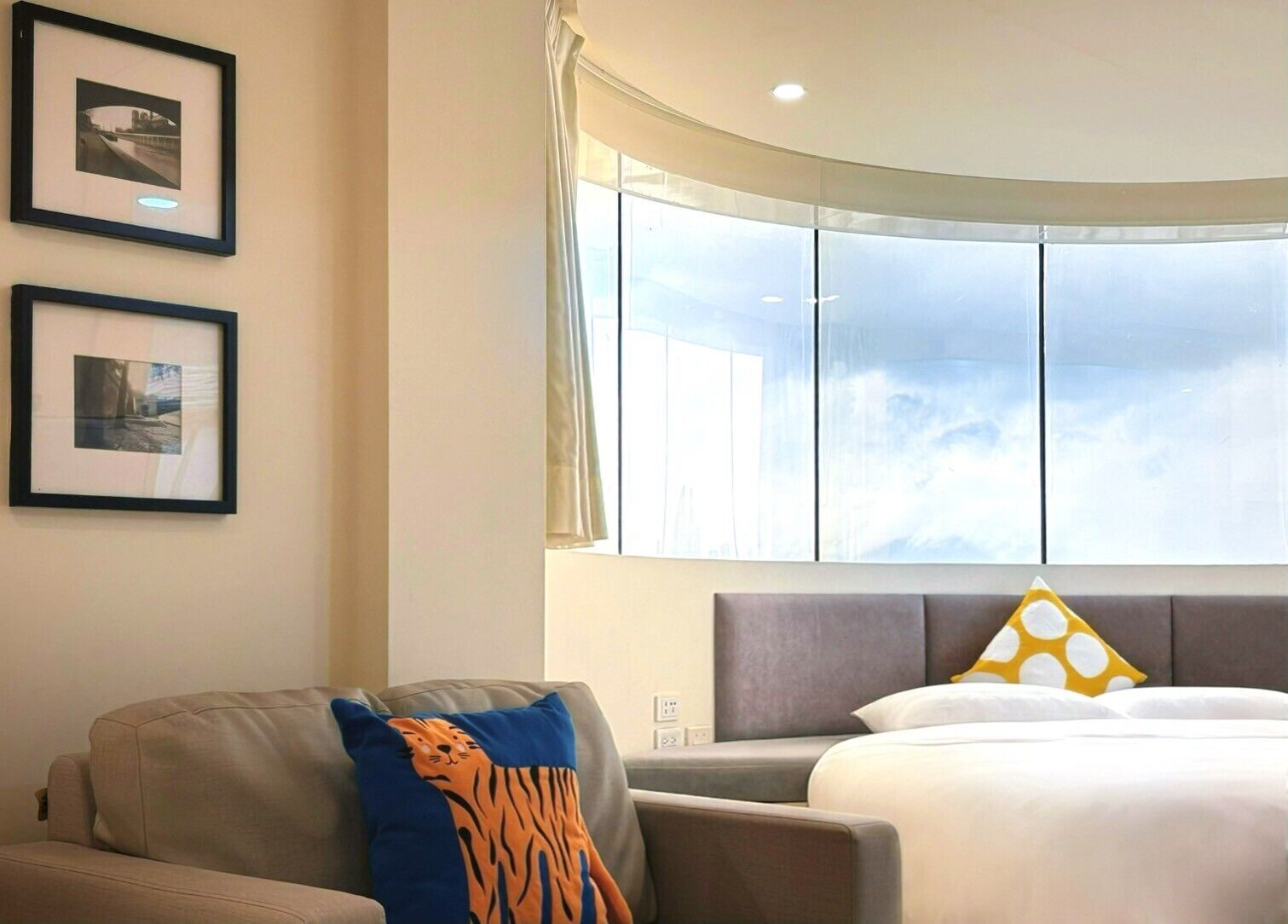 A hotel room with a bed, a sofa, and two framed pictures on the wall.