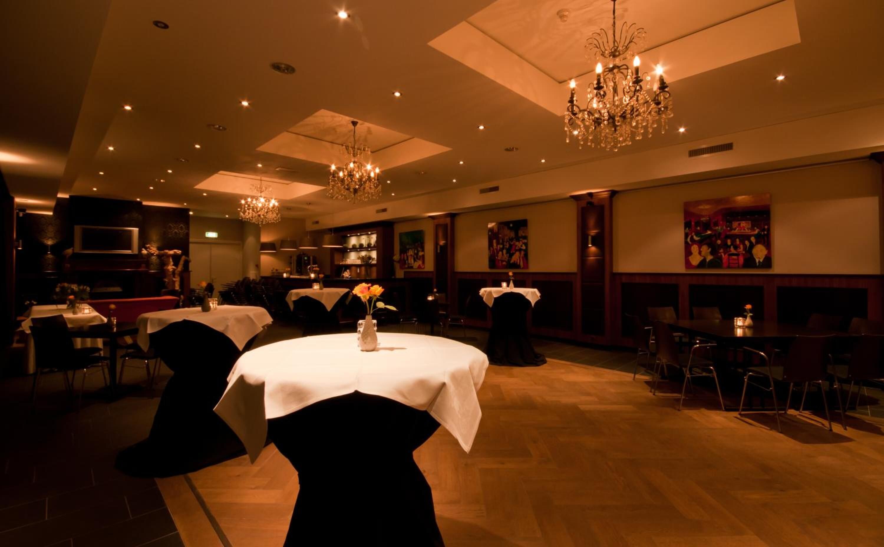 Un comedor amplio con mesas redondas, sillas tapizadas en negro y un candelabro.