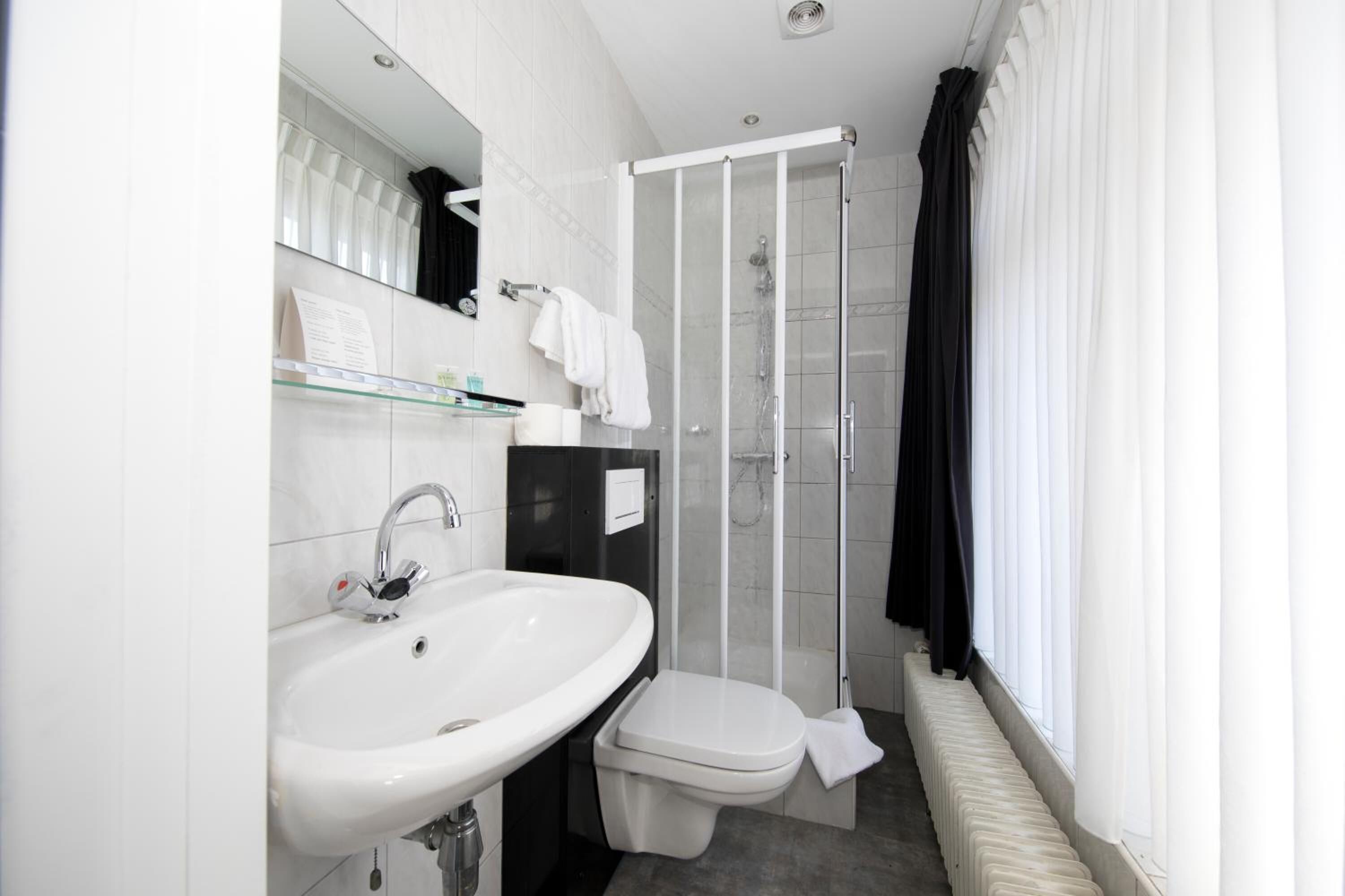 Un baño moderno con lavamanos, inodoro y cabina de ducha de vidrio.