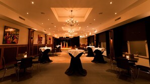 A spacious banquet hall with high ceilings, chandeliers, and tables set for events. - Hotel St. Lambert (Helmond)