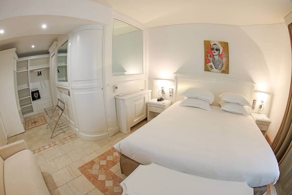 Quarto de hotel com uma cama grande, guarda-roupa, penteadeira e banheiro.