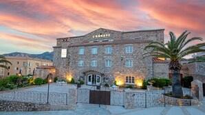 A stone building with a sign reading "L'ABBAYE" and a courtyard with outdoor seating.