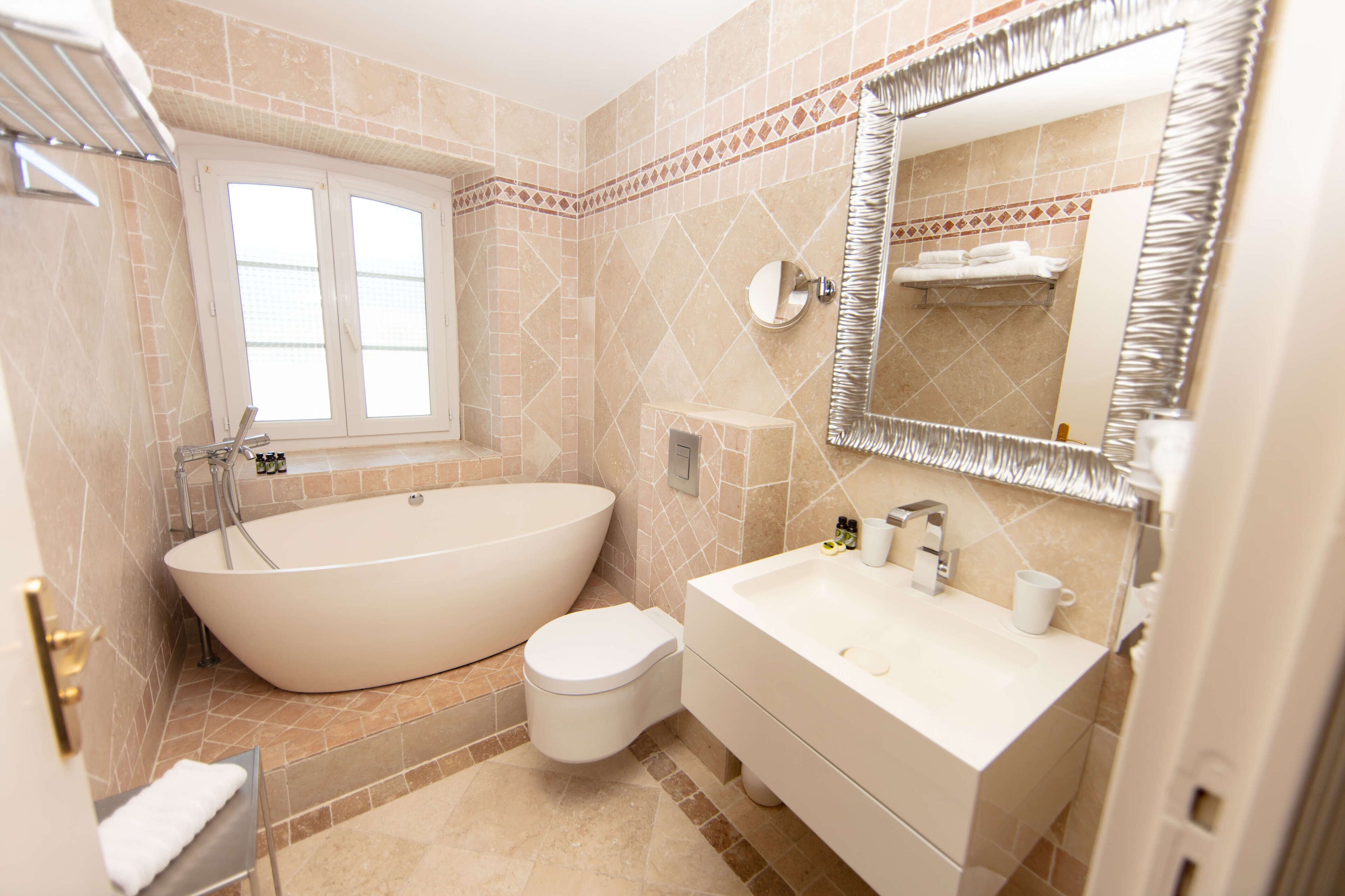 A bathroom with a freestanding bathtub, a toilet, a sink, and a mirror.