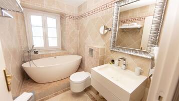 A bathroom with a freestanding bathtub, a toilet, a sink, and a mirror.