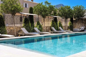 A pool with lounge chairs and a stone wall. - Hotel l'Abbaye (Calvi)