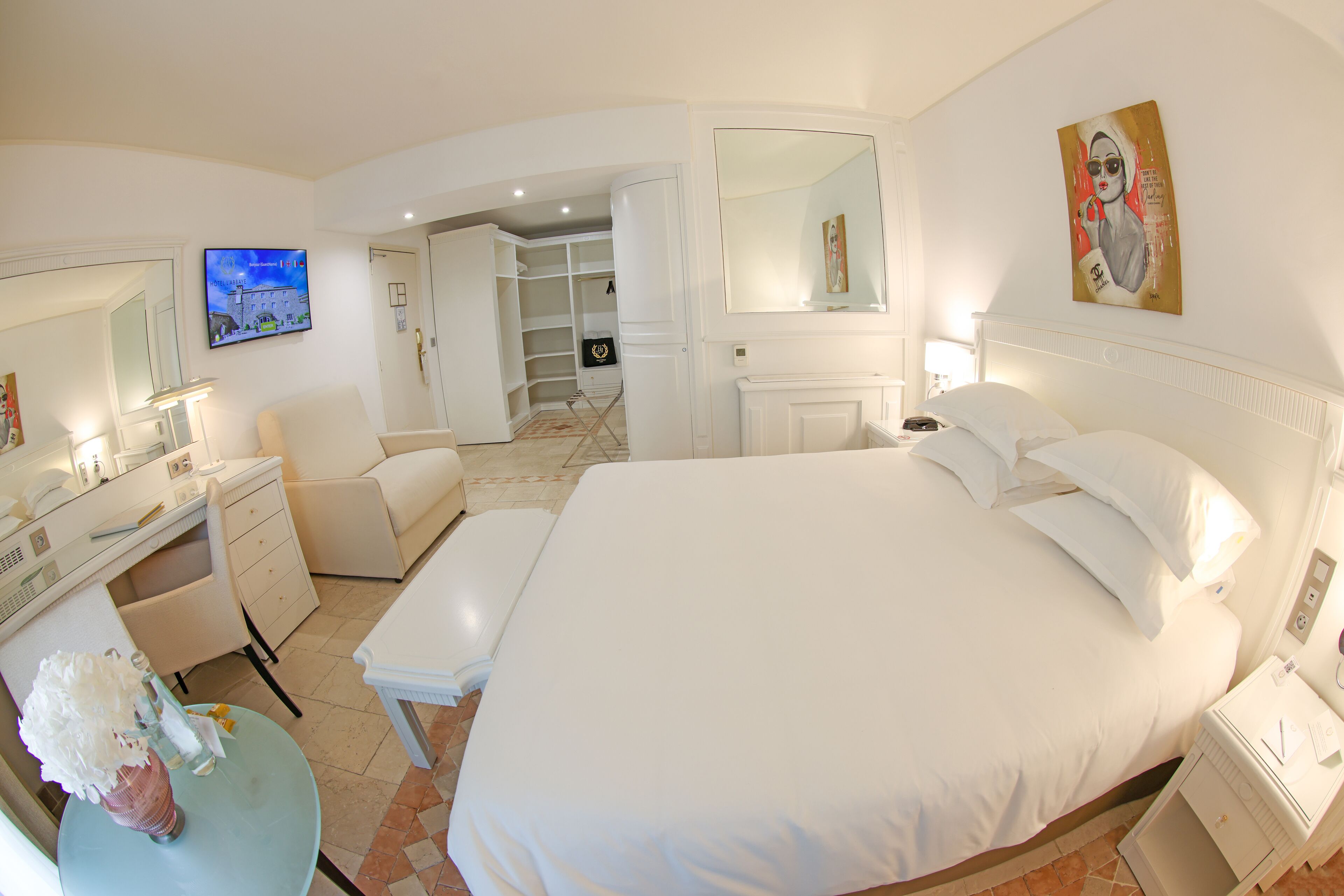 Un dormitorio amplio con una cama grande, una mesita de noche, un escritorio con silla, un tocador con espejo y un vestidor.