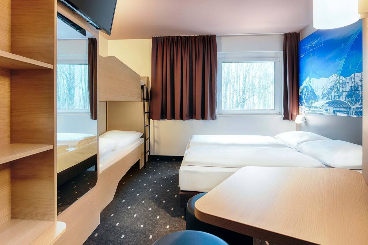 A hotel room with two beds, a TV, and a window with curtains.