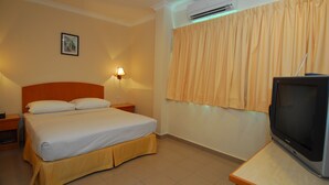A hotel room with a bed, a nightstand, a lamp, an air conditioner, and a television. - Hotel City Star (Sandakan)