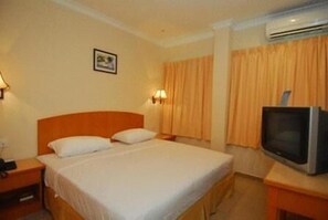 Habitació d'hotel amb un llit individual, una taula de nit, una televisió i aire condicionat fixat a la paret.
