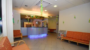 A reception area with a counter, chairs, and a sofa. - Hotel City Star (Sandakan)