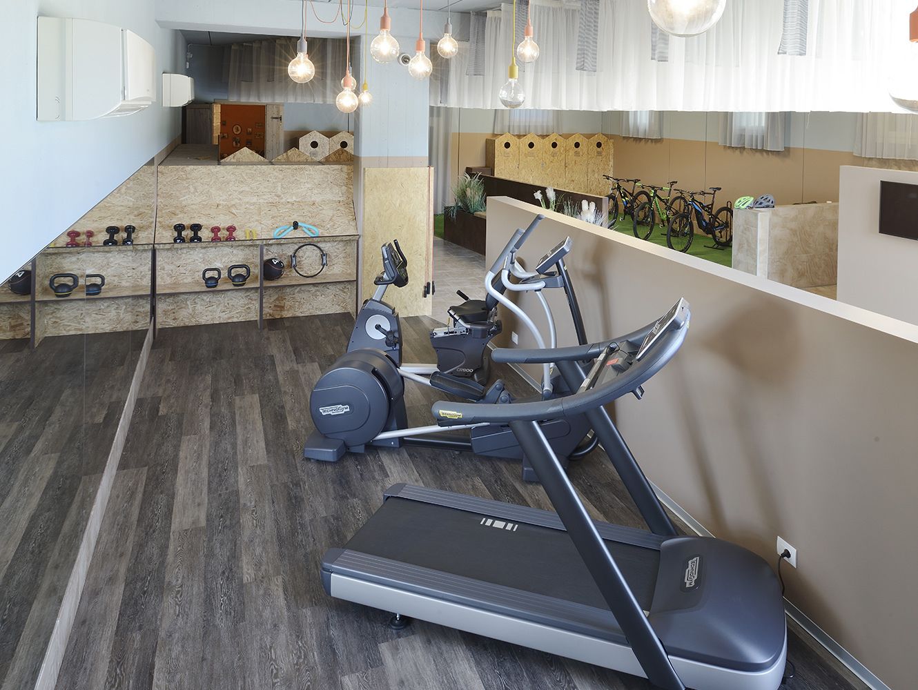 Un gimnasio en casa con cintas de correr, bicicletas estáticas y equipo de pesas.