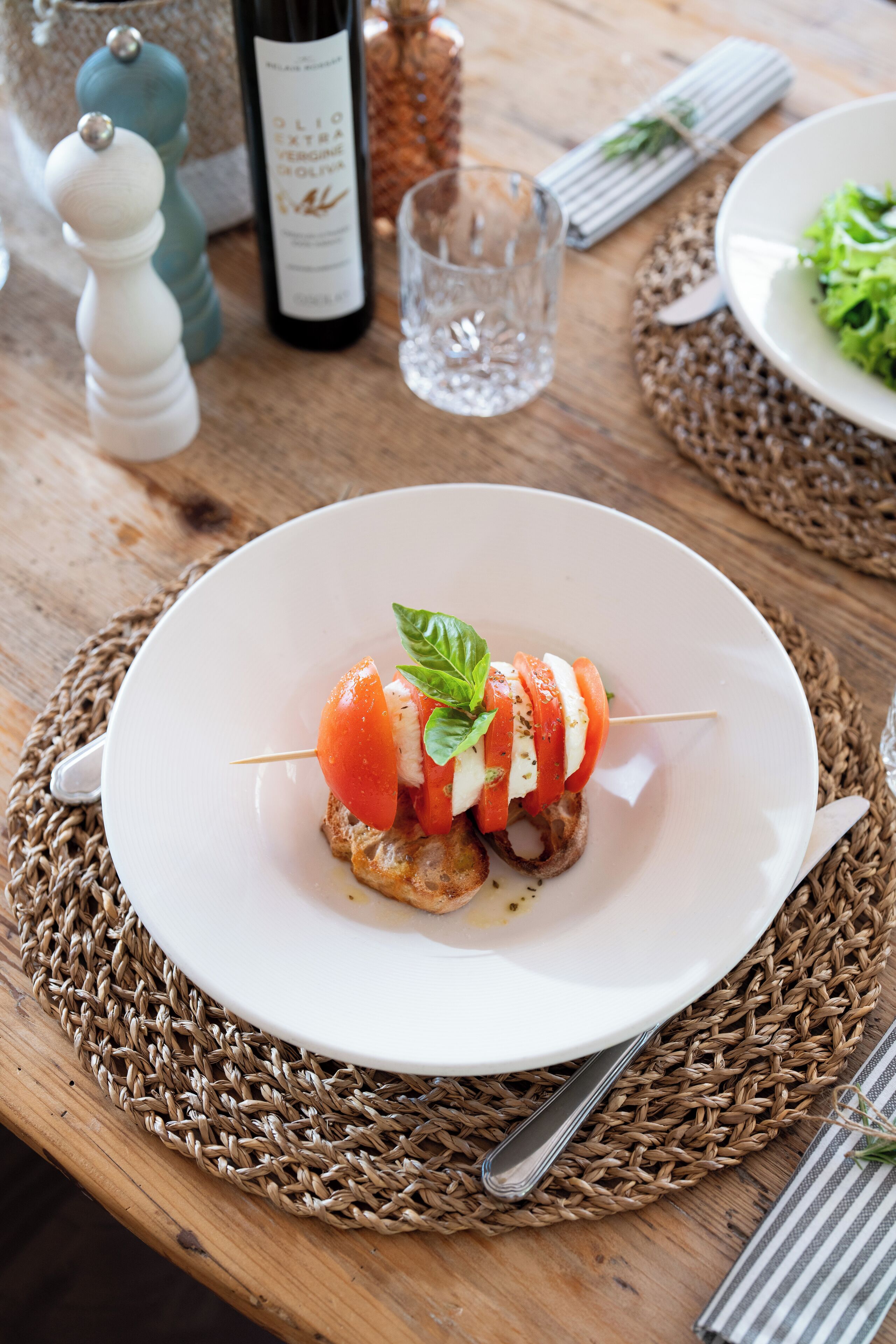 A plate of tomato and mozzarella skewers on a woven placemat.
