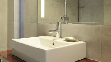 A modern bathroom with a white sink, a glass shower enclosure, and a large mirror.