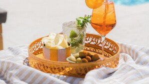 Un plateau avec une boisson, des glaçons et des en-cas, placé près d’une piscine.