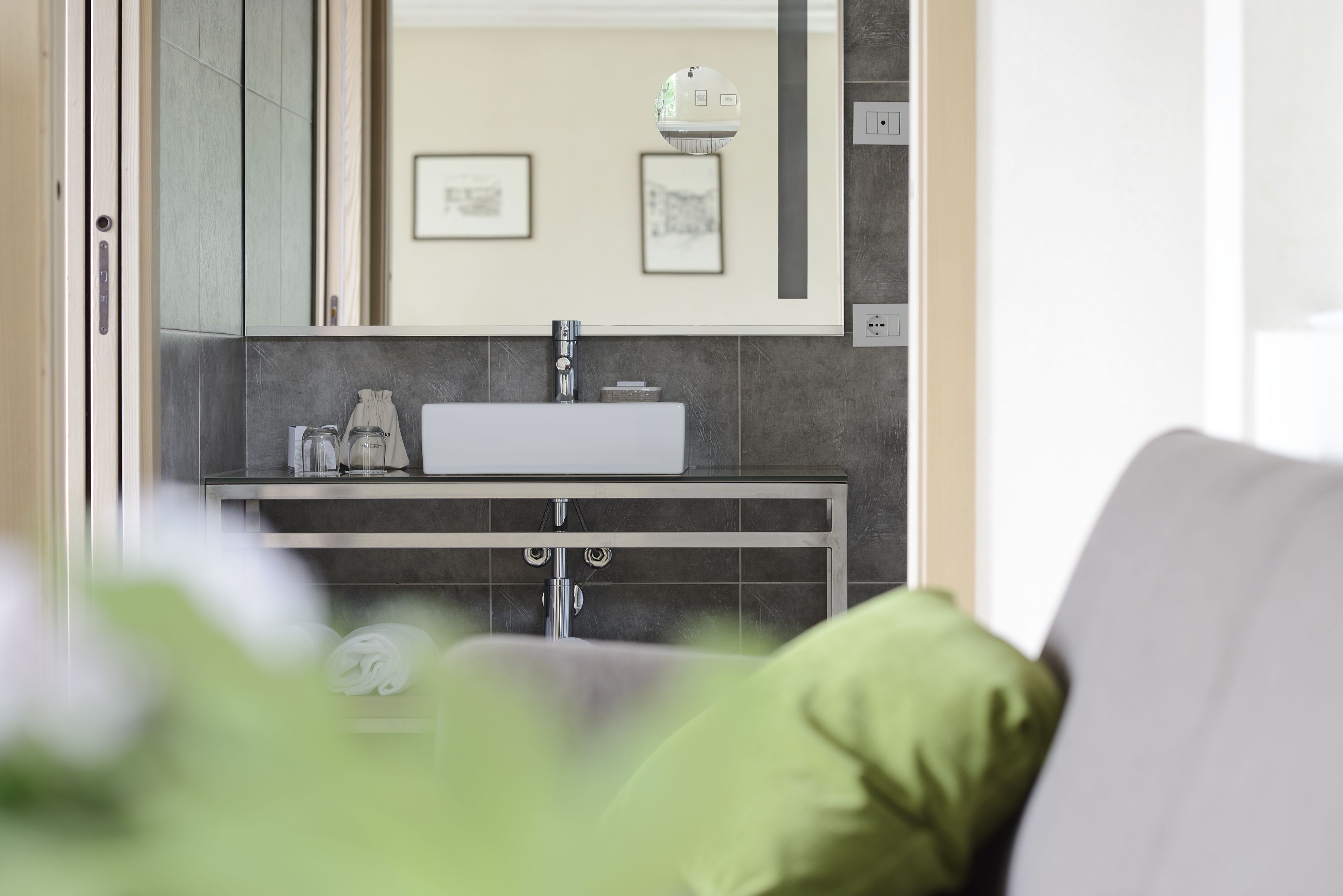 A modern bathroom with a large mirror, a sink, and a toilet. There are framed pictures on the wall and a towel rack.
