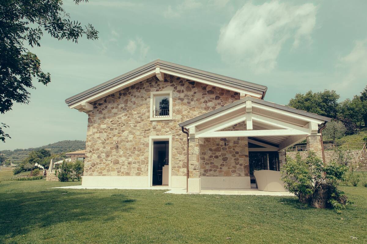 A stone house with a covered porch, a small window, and a door.