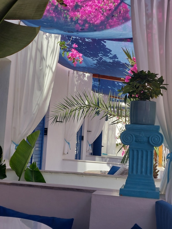A room with a blue column, white curtains, and a potted plant.