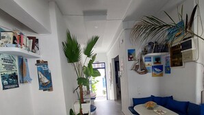 Vestíbulo de hotel con paredes blancas, sofás azules, suelo de mármol y plantas en macetas.