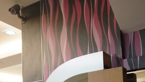 A reception desk with a white telephone, a modern design with a curved structure, and a patterned wall in the background. - Safari Hotel (Ampang)