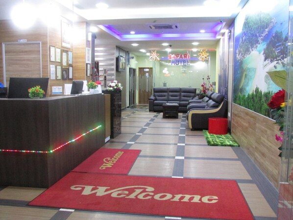 A hotel reception area with a reception desk, a check-in counter, a seating area with sofas, and a welcome mat. - Safari Hotel (Ampang)