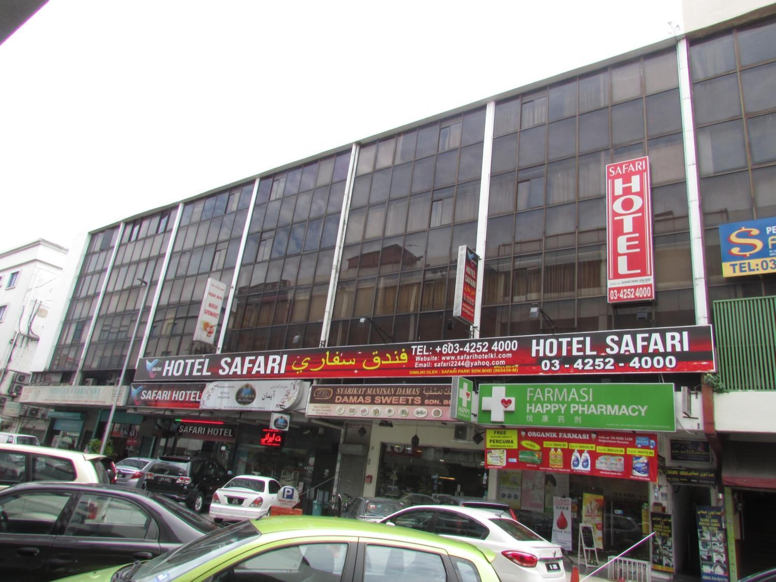 A building with multiple signs for Hotel Safari, including contact information and a website.