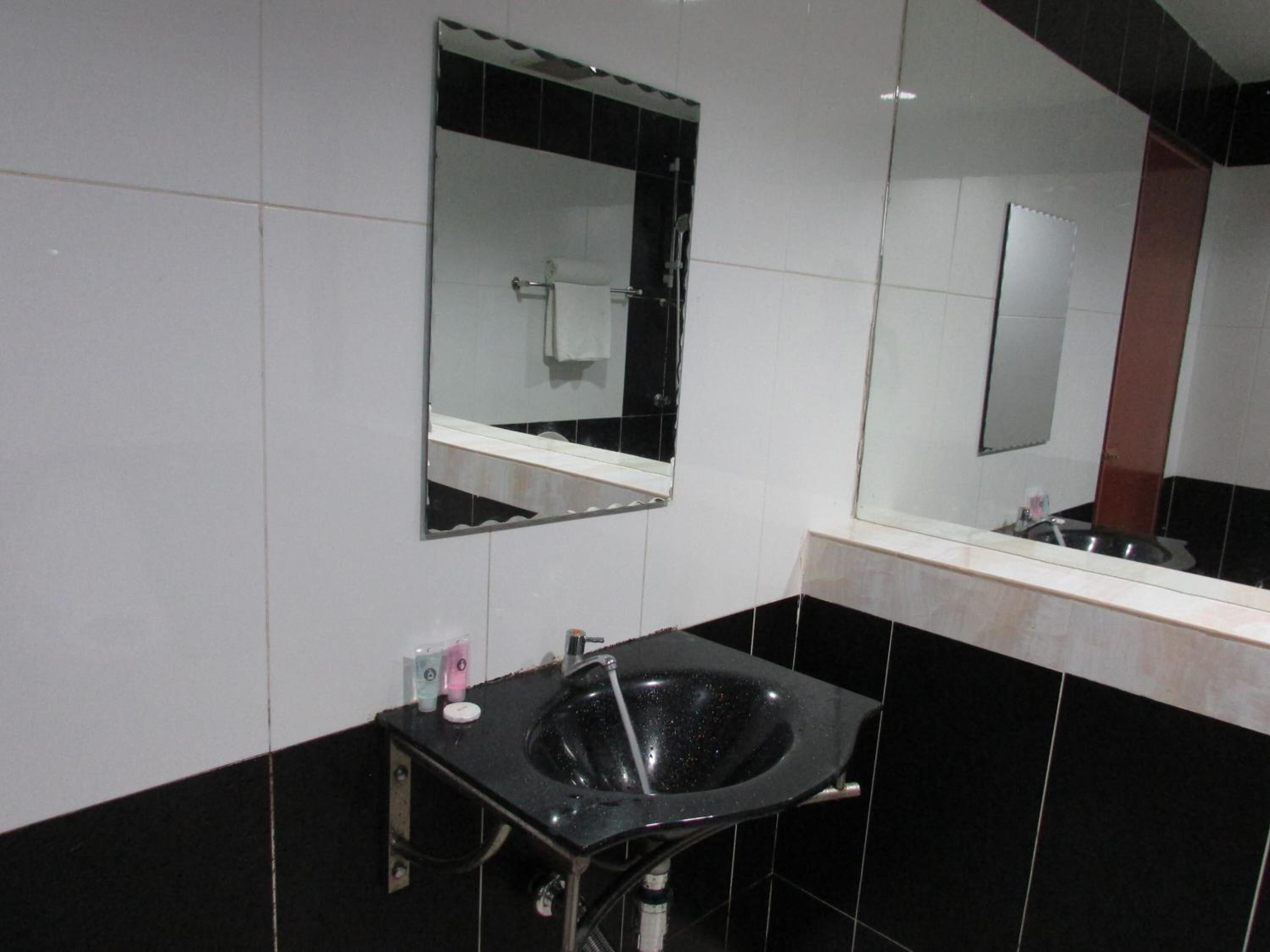 Une salle de bain moderne avec un lavabo noir, un miroir et un porte-serviettes.