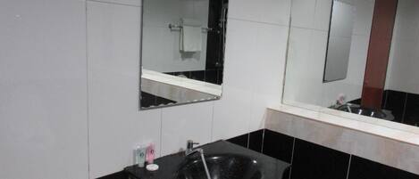 Un baño moderno con un lavabo negro, un espejo y un perchero para toallas.