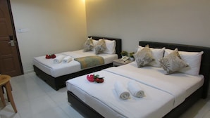 A hotel room with two beds, each with white linens and decorative pillows. There is a small table with a phone and a vase of flowers. - Safari Hotel (Ampang)