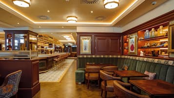 Una zona de bar con mobiliario de madera, un banco acolchado verde y una barra con taburetes.