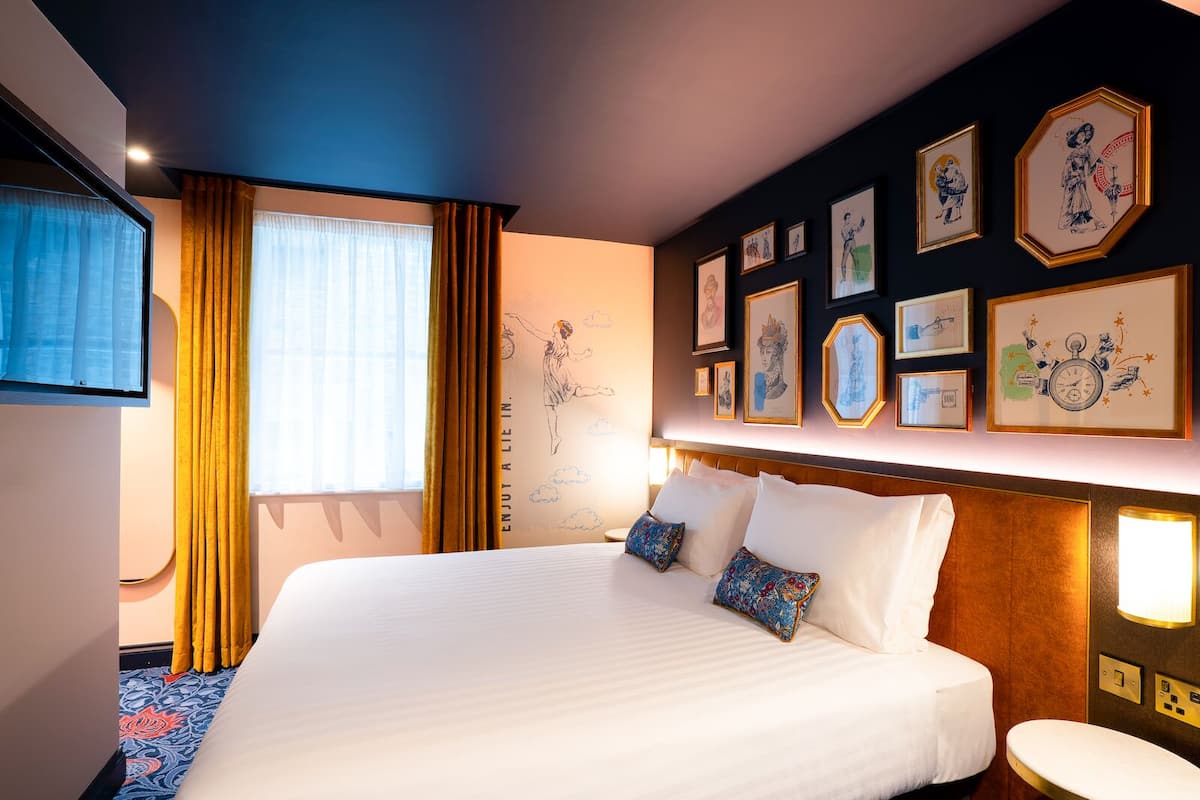 Une chambre d’hôtel avec un grand lit, une télévision et un mur décoré d’œuvres d’art encadrées.