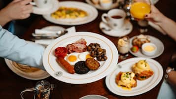 Une table mise pour le petit-déjeuner, avec des assiettes remplies de nourriture, des tasses et une théière.