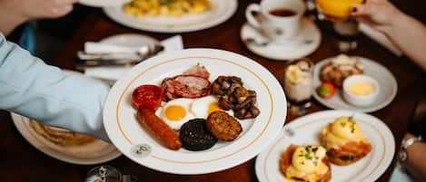 A breakfast setting with plates of food, cups, and a teapot.