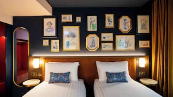 Une chambre d’hôtel avec deux lits, un grand miroir et des œuvres d’art accrochées aux murs.