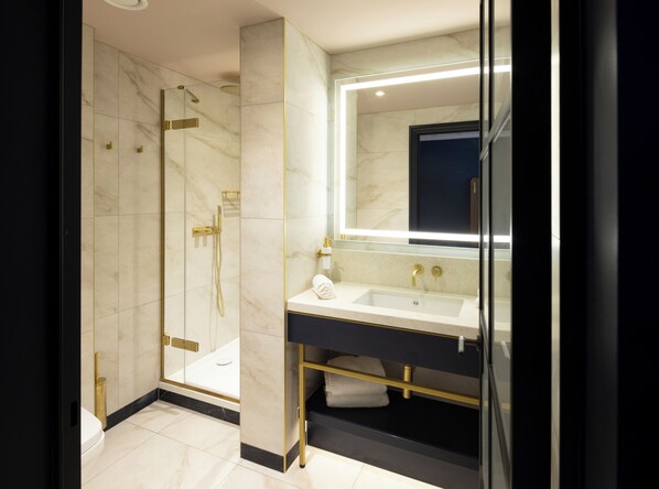 A modern bathroom with a glass-enclosed shower, a sink with a mirror, and a towel rack. - The Mercantile Hotel (Dublin)