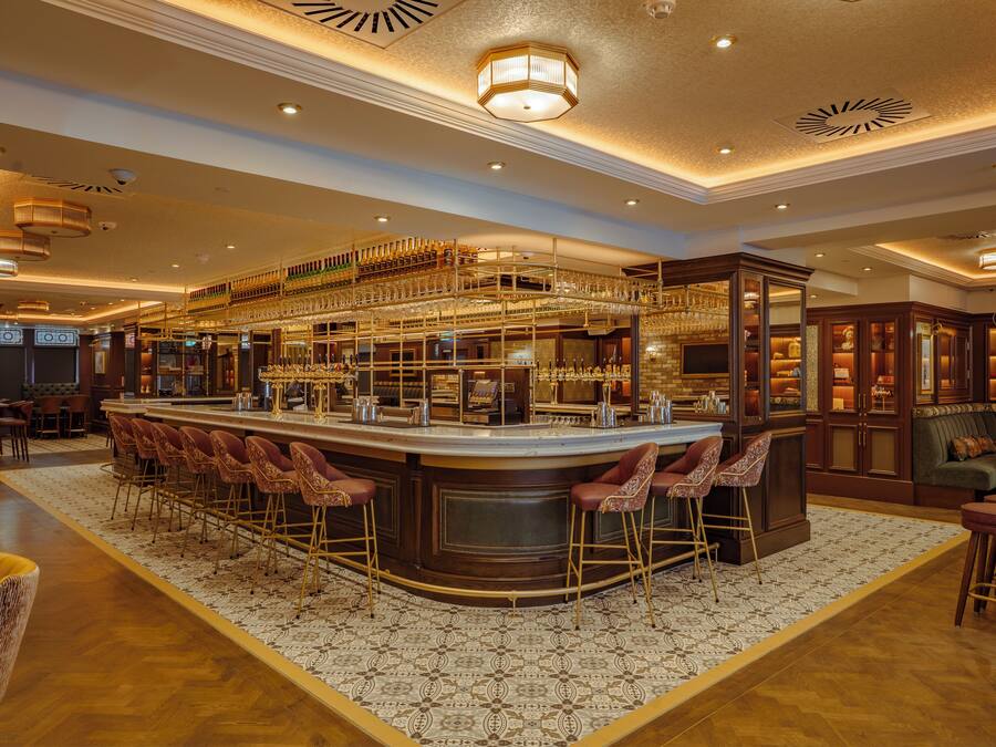 A bar area with a central bar, multiple stools, and a patterned rug.