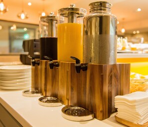 A buffet setup with multiple beverage dispensers and stacked plates. - Horizon Inn (Taipei)