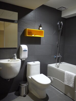 A modern bathroom with a white sink, toilet, and bathtub. There is a yellow shelf above the toilet and a hand dryer on the wall. - Horizon Inn (Taipei)