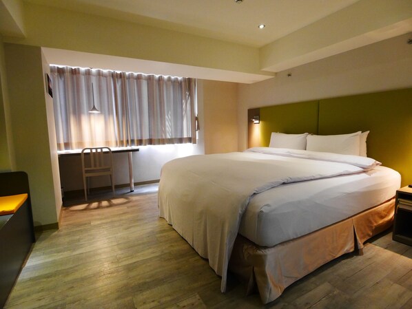 A hotel room with a large bed, a desk, and a chair. - Horizon Inn (Taipei)